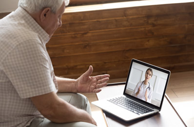 Older man talking to woman on computer